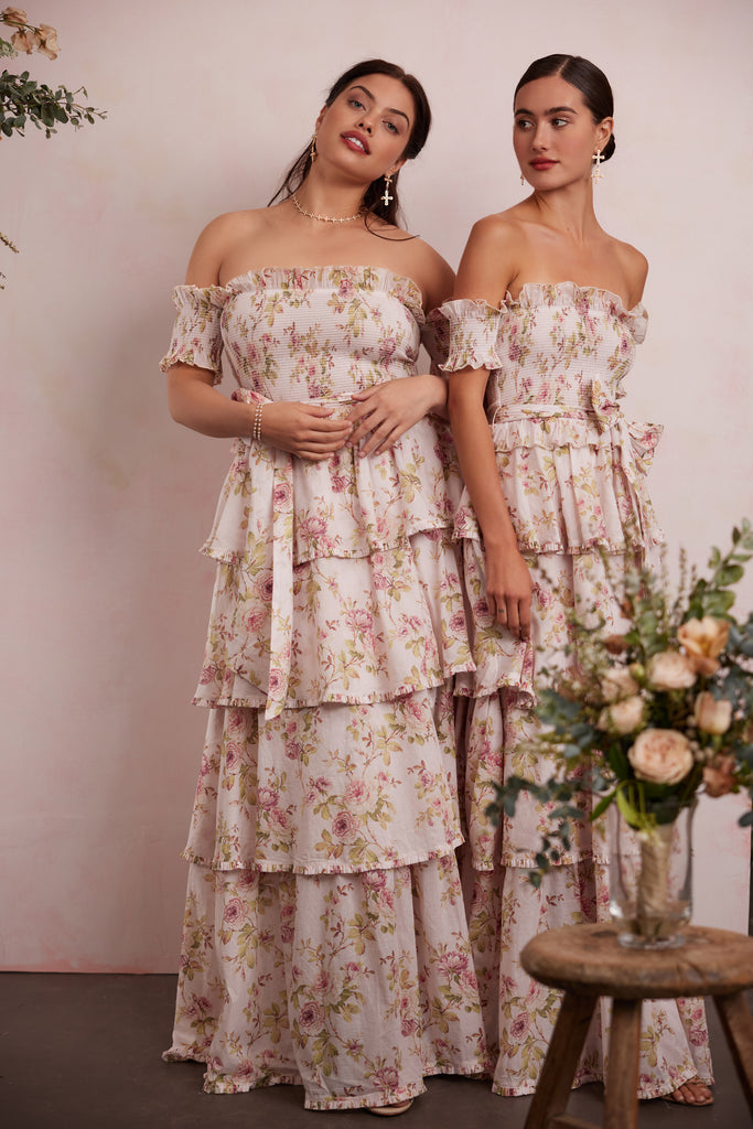 two models both wearing the angelina dress in pink rose print. left model showing full front view. right model showing 3/4 front view.