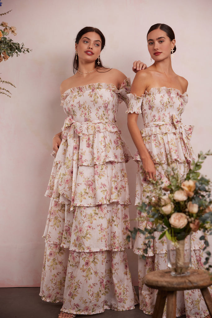two models both wearing the angelina dress in pink rose print. left model showing full front view. right model showing 3/4 side view.