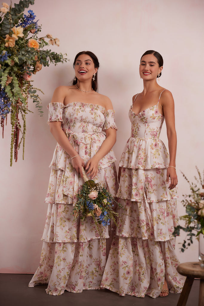 two models wearing dresses in pink rose print. right model showing full front view wearing angelina dress in pink rose print. right model showing full side view wearing caterina dress in pink rose print.