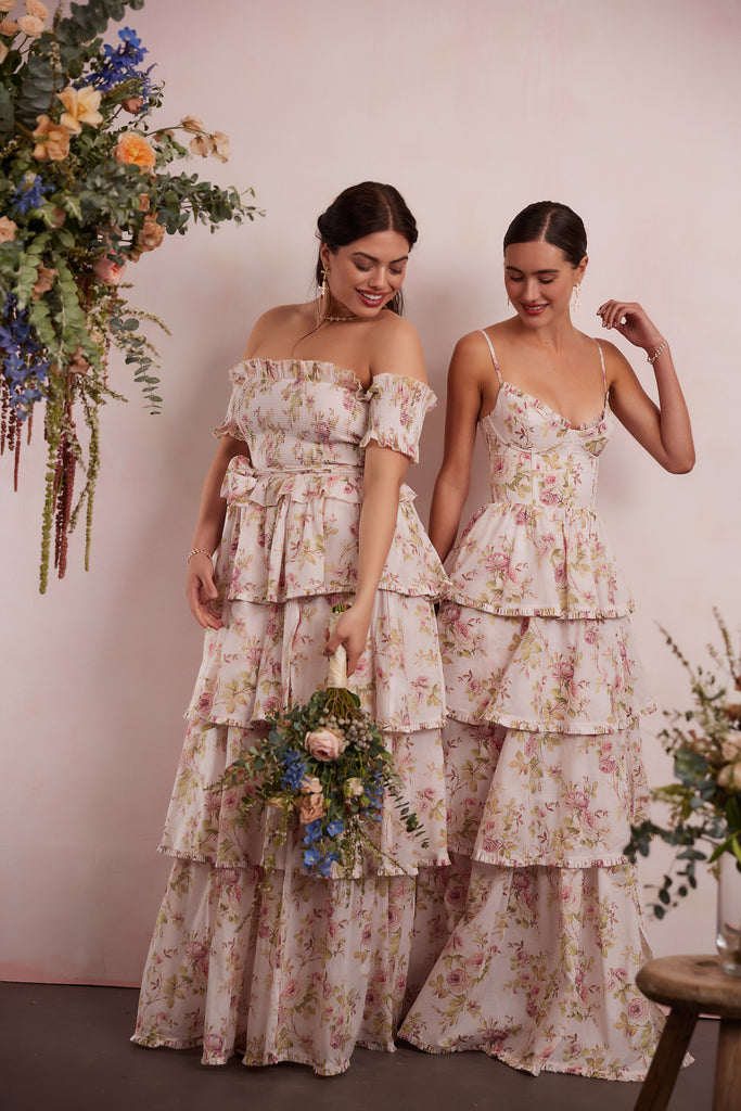 two models wearing dresses in pink rose print. right model showing full front and side view wearing angelina dress in pink rose print. right model showing full front and side view wearing caterina dress in pink rose print.