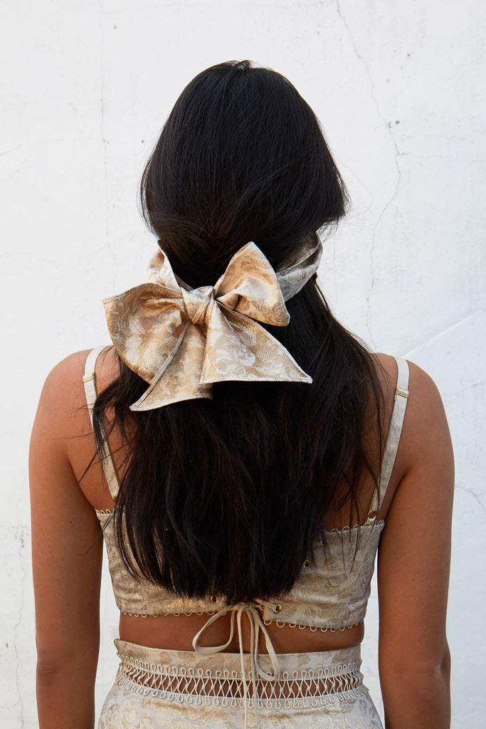 full back view of model wearing bow facemask in duchess lamé.