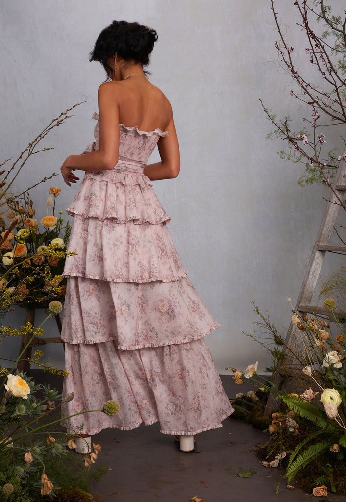 walking full back view of model wearing angelina dress in blush bouquet with detachable sleeves taken off to show strapless version of dress.