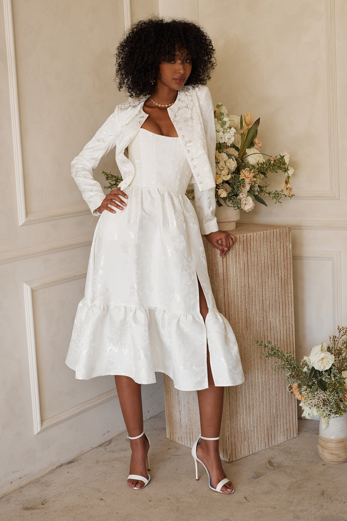 front view of model wearing The Audrey Jacket in Coconut Macaron over The Virginia Dress in White Baroque Floral.