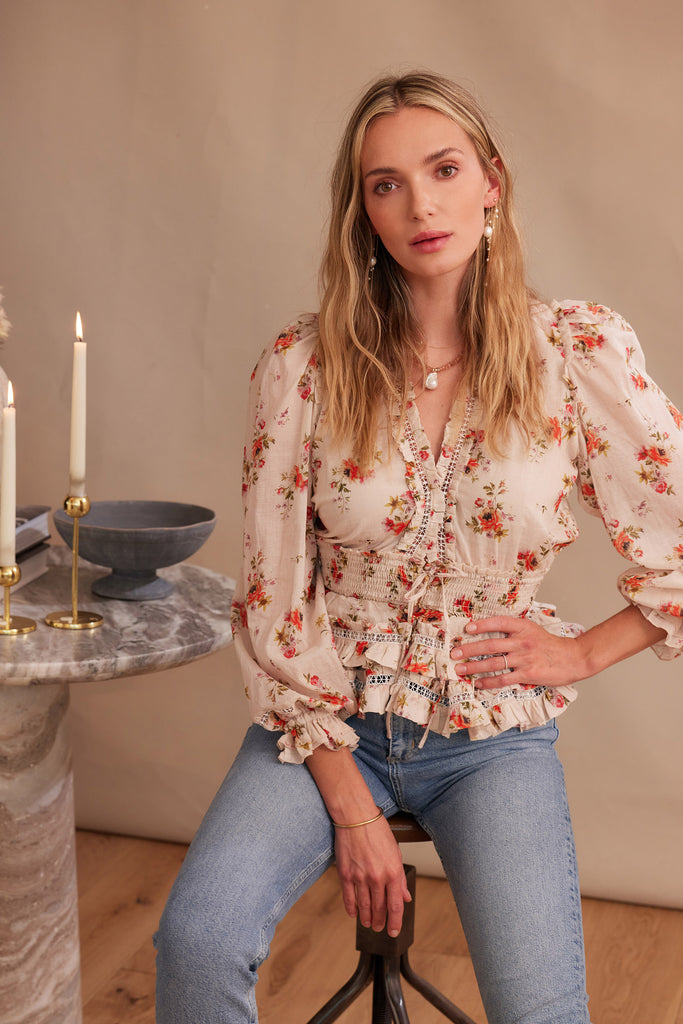 3/4 front view of model wearing allegra top in natural dainty floral with jeans. model sitting in chair