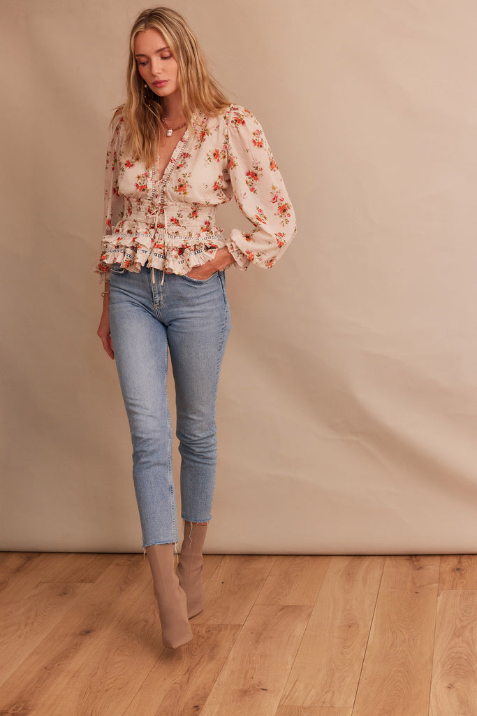 walking front view of model wearing the allegra top in natural dainty floral with jeans and boots.