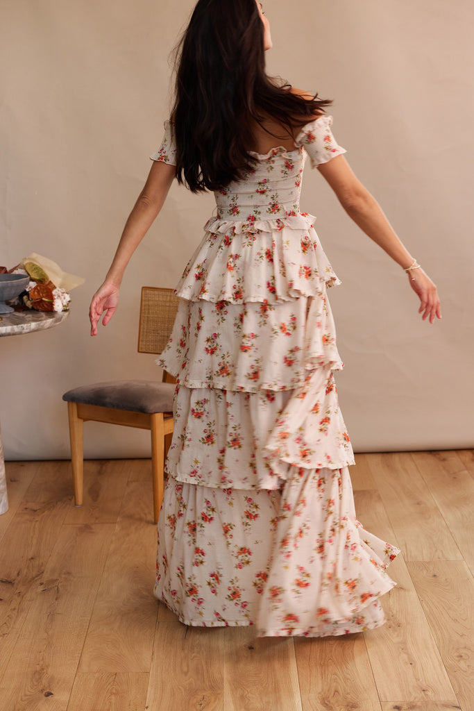 walking full back view of model wearing angelina dress in natural dainty floral.