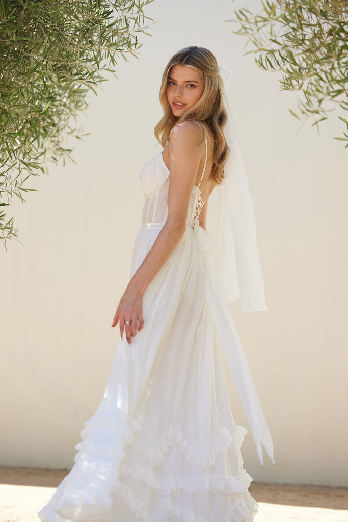 side view of model wearing carmen dress in white.